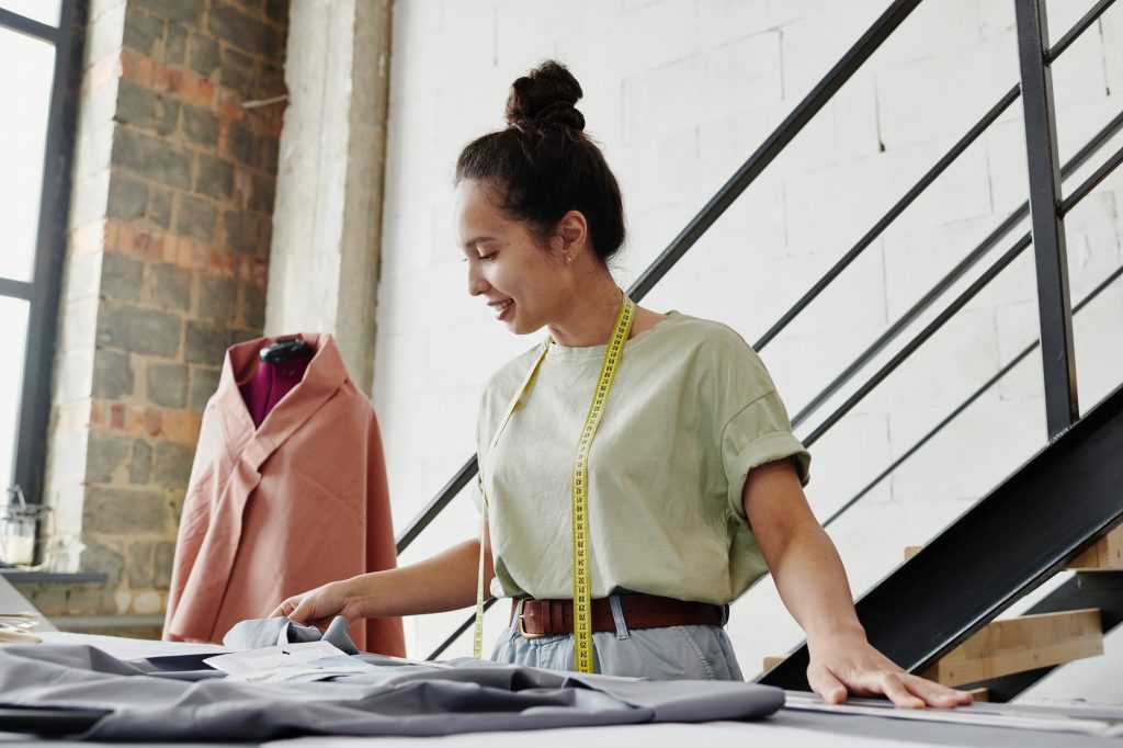 Self-employed fashion designer looking at sketch of seasonal collection items